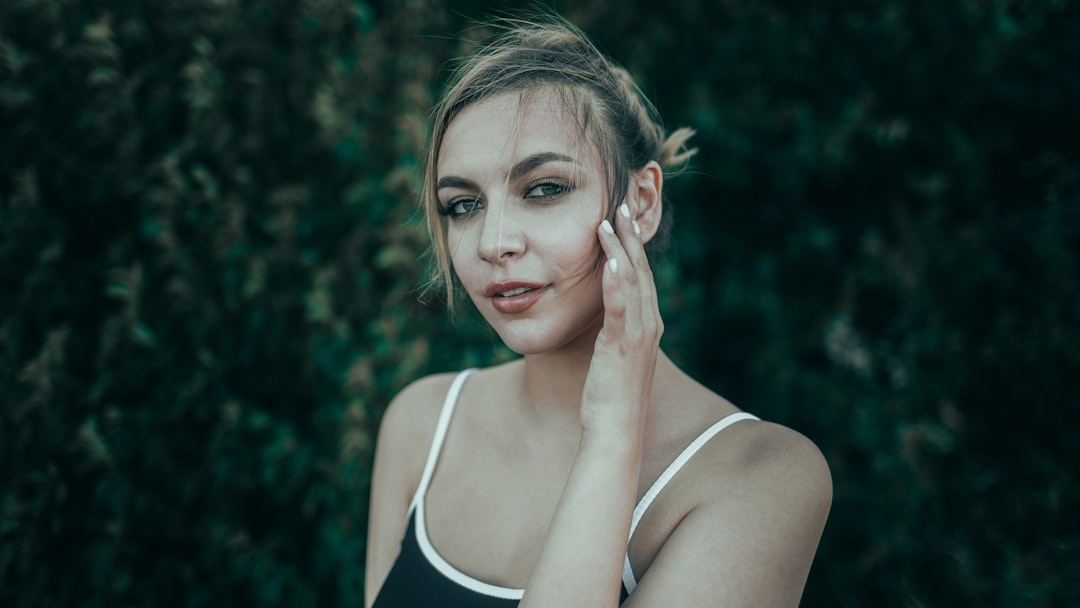 Young woman with hand on cheek looking at camera