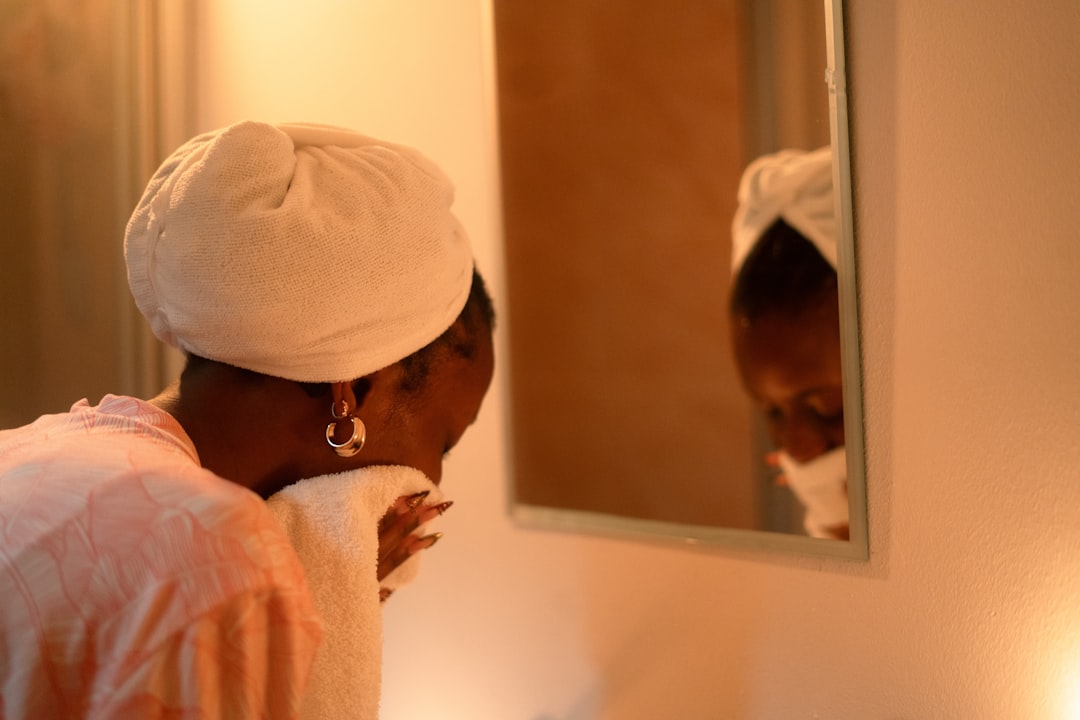 Woman drying her face with a towel in the mirror
